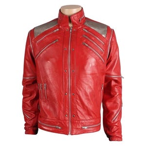 May include: A vibrant red leather jacket with multiple silver zippers and a high collar. The shoulders feature a silver sequined design. The jacket has a fitted silhouette and a classic biker style, perfect for a bold fashion statement.