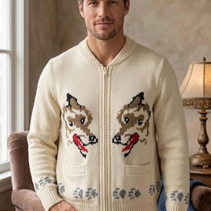 Könnte beinhalten: Cremefarbener Reißverschluss-Pullover mit einem sich wiederholenden Hundegesicht-Design auf der Vorderseite. Der Pullover hat zwei Vordertaschen und ein Muster aus Pfotenabdrücken am unteren Rand. Das Model trägt blaue Jeans.