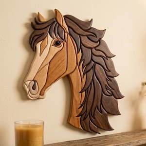 May include: Wooden horse head wall art. The artwork features a detailed mosaic design with various shades of brown wood. The horse's mane is a darker brown, contrasting with the lighter tones of the face. The piece is mounted on a beige wall.