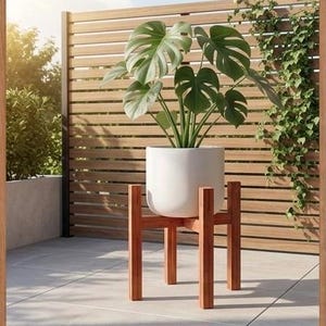 May include: A white plant pot holding a large green plant is placed on a wooden plant stand. The stand has a simple, modern design. The image has the text "MODERN SCANDINAVIAN" and "A NATURAL TOUCH FOR YOUR LIVING ROOM - MODERN PLANT STAND".