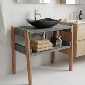 May include: A bathroom vanity featuring a matte black, wave-shaped vessel sink mounted on a gray-stained wooden frame with light brown legs. The vanity includes an open lower shelf holding a stack of three folded beige towels and a glass bottle.