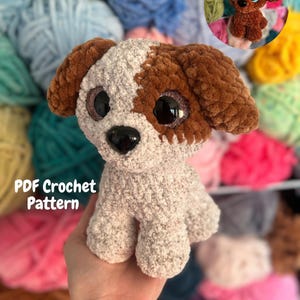 May include: A plush crochet puppy toy made with textured beige and brown yarn, featuring large black plastic eyes and a black nose. The text PDF Crochet Pattern is visible on the left side, and a small circular inset shows the puppy from above.