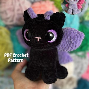 Puede incluir: Una criatura de peluche tejida a ganchillo en color negro con grandes ojos morados brillantes, pequeños cuernos morados y alas moradas texturizadas. El texto PDF Crochet Pattern es visible a la izquierda. Un pequeño recuadro circular muestra un peluche similar.
