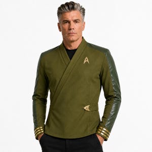 Op de afbeelding: Een olijfgroen wikkeljasje met een zwart ondershirt, een gouden Starfleet delta-insigne op de borst, een gouden gesp aan de zijkant en mouwboorden met gouden strepen. De mouwen zijn gemaakt van glad, donker olijfgroen materiaal.