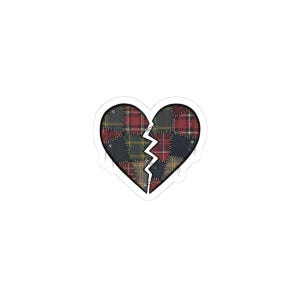 May include: A sticker featuring a broken heart design. The heart is composed of various plaid fabric patches in red, green, black, and yellow. A white jagged line splits the heart in two, with a white border.