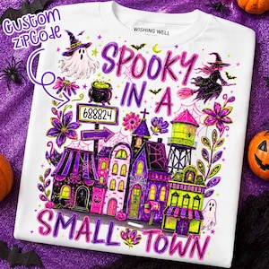 Puede incluir: Una camiseta blanca con un gráfico colorido de Halloween con el texto "SPOOKY IN A SMALL TOWN" y "CUSTOM ZIPCODE". El diseño incluye un fantasma, una bruja en una escoba, un caldero, un letrero con "688824" y edificios de color morado y verde.