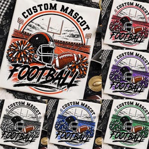 Puede incluir: Una camiseta blanca con un gráfico de un estadio de fútbol americano, un casco, un balón y pompones. El texto CUSTOM MASCOT y FOOTBALL está impreso en negro. El diseño está disponible en variaciones de color naranja, rojo, morado, azul y verde.