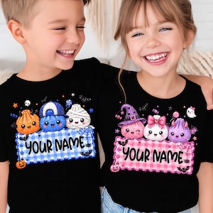 May include: Two black t-shirts featuring Halloween-themed graphics. One shirt displays blue plaid with cartoon characters and the text YOUR NAME. The other shirt features pink plaid with cartoon characters and the text YOUR NAME.