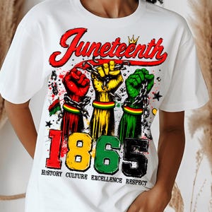 May include: White t-shirt with a graphic design celebrating Juneteenth. The design features three fists in red, yellow, and green, chained together, with the word "Juneteenth" in red script above the year "1865". The shirt also includes the words "History Culture Excellence Respect".