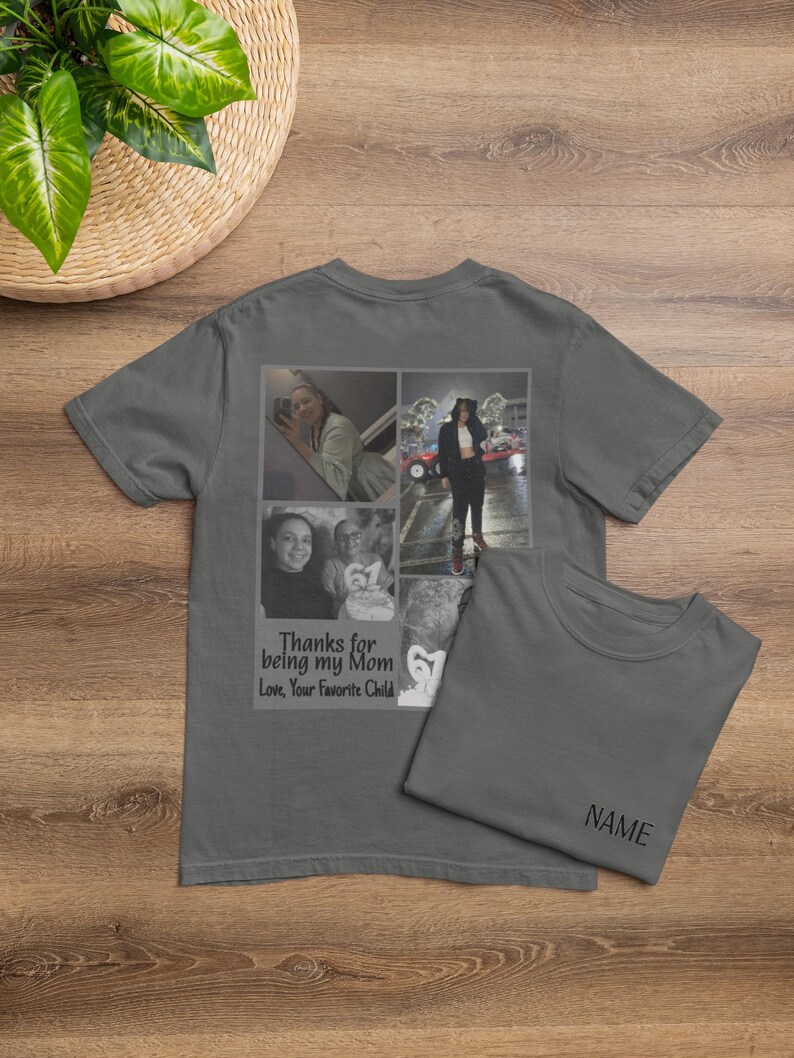 May include: Gray t-shirt with a collage of photos and the text "Thanks for being my Mom, Love, Your Favorite Child." A second t-shirt is folded next to it, with the word "NAME" printed on it. The shirts are on a wooden surface.