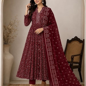 May include: A deep maroon ankle-length dress featuring a white geometric wave pattern, a mandarin collar with vertical embroidery, long sleeves, and a matching sheer dupatta with a circular border print, paired with solid maroon trousers.