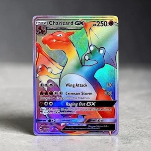 May include: A holographic Charizard GX trading card featuring a rainbow-colored dragon illustration. The card displays 250 HP, Wing Attack, Crimson Storm, and Raging Out GX moves. Text includes stage 2, evolves from Charmeleon, and card number 150/147.