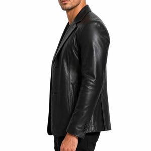 May include: A black leather blazer with a notched lapel and two-button closure. The blazer has a tailored fit and features three buttons on each cuff. The garment is worn over a black shirt and black pants.