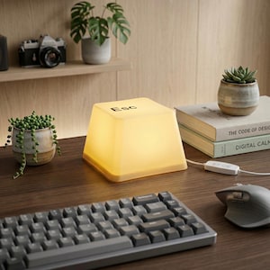 May include: A white ceramic mug with a black handle and the text "But First, Coffee" in a bold, black font. The mug is sitting on a wooden surface. The mug is approximately 4 inches tall.