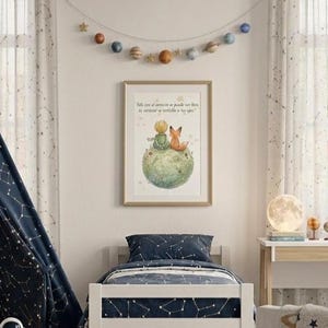 Puede incluir: Un dormitorio infantil con una tienda tipi azul marino con un diseño de constelación, una cama con una colcha a juego y una impresión enmarcada de El Principito. Una guirnalda de planetas cuelga sobre la cama y una cesta de mimbre contiene juguetes.