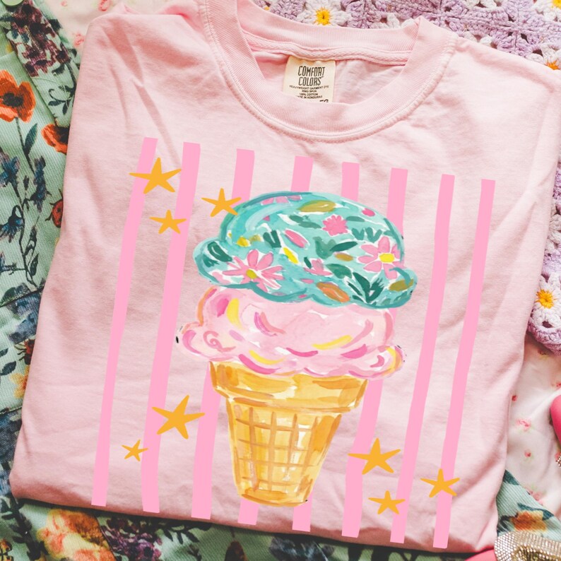 Retro pastel striped png featuring double scoop pastel ice cream cone top scoop has floral pattern and bottom scoop is pink.  Background stripes are pink yellow stars scattered.   Shown here on a folded blossom tee.
