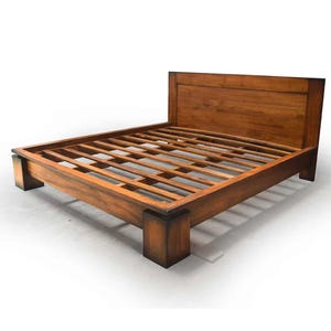 May include: A wooden bed frame with a headboard. The bed frame is made of dark brown wood and has a slatted base. The headboard is a solid panel of wood. The bed frame is rectangular and sits on four square legs.