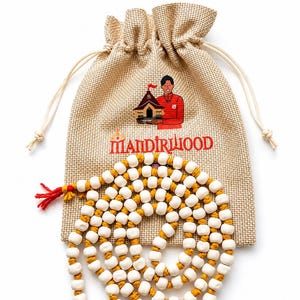 Puede incluir: Una bolsa de cordón beige de tela texturizada con un gráfico de una persona sosteniendo un templo y el texto MANDIRILOOD. Una larga hilera de cuentas blancas separadas por nudos en un cordón amarillo mostaza con una borla roja al final.