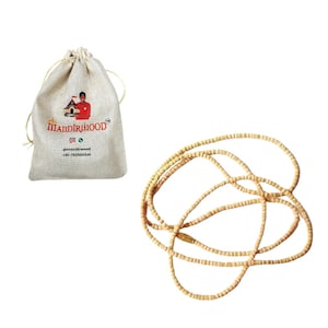 May include: A beige drawstring bag with the text "Mandiriwood" and a logo of a person holding a building. A light brown beaded necklace is also in the image.
