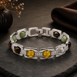 Puede incluir: Una pulsera de eslabones plateados con segmentos metálicos rectangulares alternados y cuentas esféricas de piedras preciosas. Las cuentas incluyen piedras translúcidas amarillas, claras, marrón oscuro y verde pálido. Cristales incrustados.