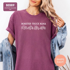 Berry Comfort Colors t-shirt featuring the text "MONSTER TRUCK MAMA" and four white monster truck designs. The shirt has a crew neck and short sleeves.