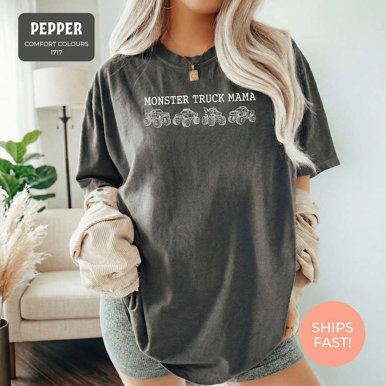 Pepper Comfort Colors t-shirt featuring the text "MONSTER TRUCK MAMA" and four white monster truck designs. The shirt has a crew neck and short sleeves.