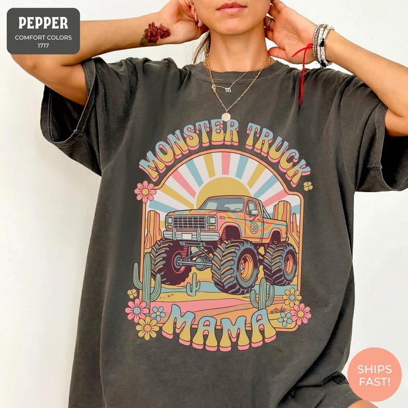 Comfort Colors graphic tee featuring a retro groovy monster truck with floral details, desert cacti, and a sunburst backdrop, arched text reading Monster Truck Mama, designed for moms of boys, Monster Jam fans, and birthday party season.