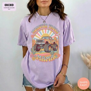 Comfort Colors graphic tee featuring a retro groovy monster truck with floral details, desert cacti, and a sunburst backdrop, arched text reading Monster Truck Mama, designed for moms of boys, Monster Jam fans, and birthday party season.