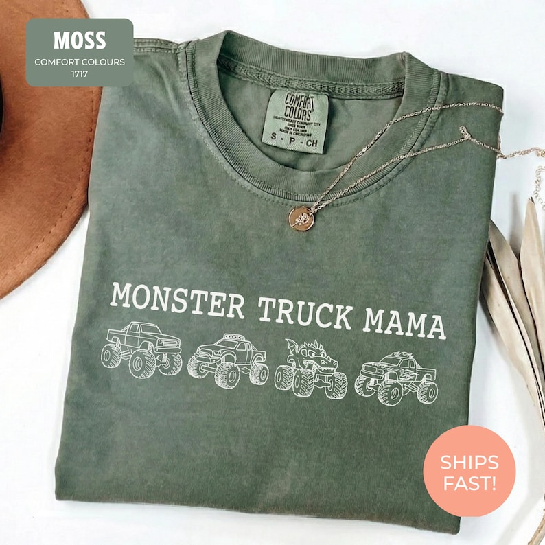 Moss Comfort Colors t-shirt featuring the text "MONSTER TRUCK MAMA" and four white monster truck designs. The shirt has a crew neck and short sleeves.