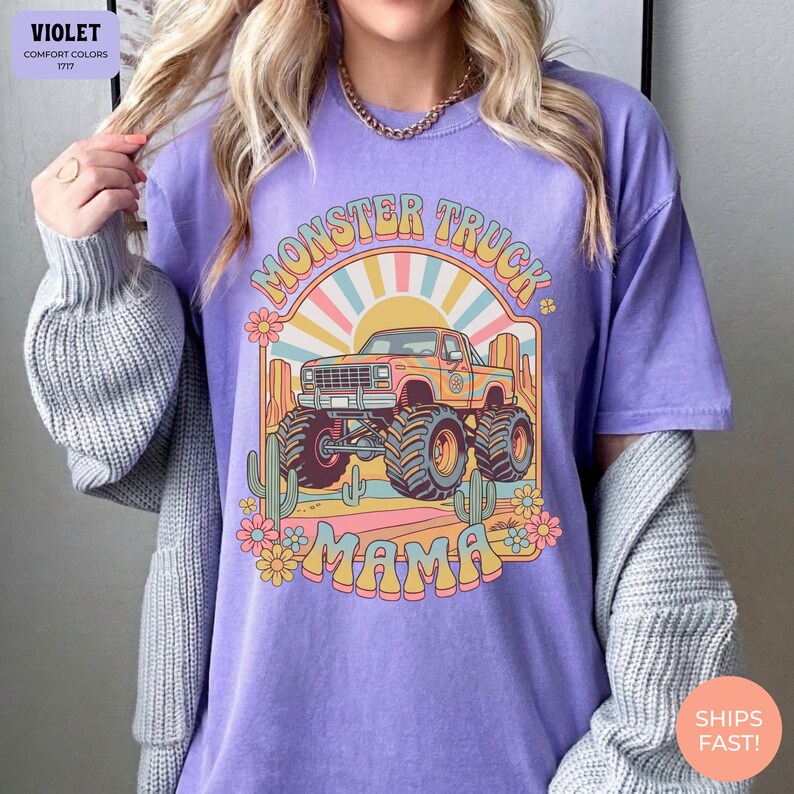 Comfort Colors graphic tee featuring a retro groovy monster truck with floral details, desert cacti, and a sunburst backdrop, arched text reading Monster Truck Mama, designed for moms of boys, Monster Jam fans, and birthday party season.