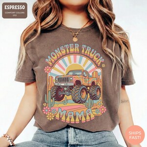 Comfort Colors graphic tee featuring a retro groovy monster truck with floral details, desert cacti, and a sunburst backdrop, arched text reading Monster Truck Mama, designed for moms of boys, Monster Jam fans, and birthday party season.