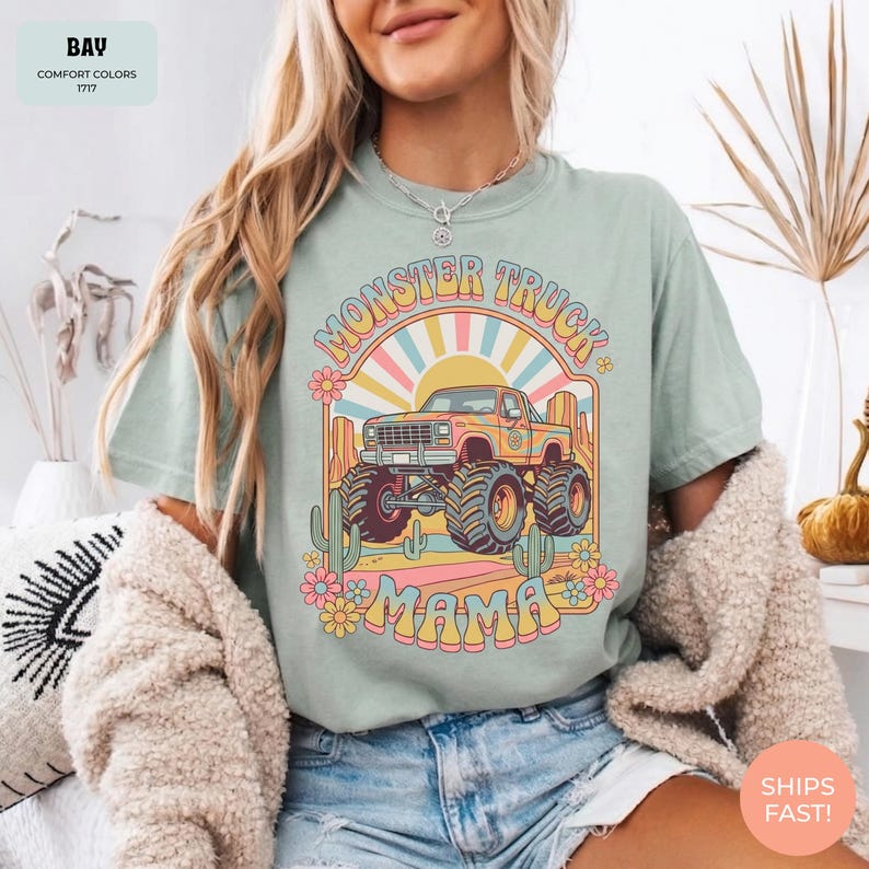 Comfort Colors graphic tee featuring a retro groovy monster truck with floral details, desert cacti, and a sunburst backdrop, arched text reading Monster Truck Mama, designed for moms of boys, Monster Jam fans, and birthday party season.