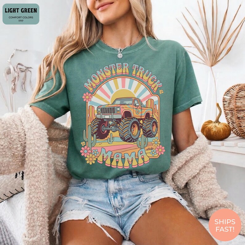 Comfort Colors graphic tee featuring a retro groovy monster truck with floral details, desert cacti, and a sunburst backdrop, arched text reading Monster Truck Mama, designed for moms of boys, Monster Jam fans, and birthday party season.