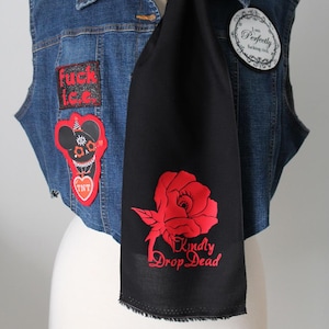May include: A blue denim waistcoat adorned with patches, including one reading "fuck i.c.c." and a cartoon mouse, paired with a black scarf featuring a red rose graphic and the text "Kindly Drop Dead" and a circular pin reading "I am Perfectly fucking civil."
