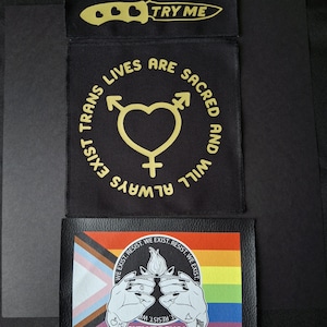 May include: Three patches with text and graphics. The top patch is black with a gold knife and the words "TRY ME". The middle patch is black with gold text and symbols. The bottom patch has a rainbow flag and the words "BURN IT DOWN."