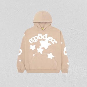 K&ouml;nnte beinhalten: Ein beigefarbener Hoodie mit einer Vordertasche und einer Kapuze. Der Hoodie zeigt den Text "sp5der" in Wei&szlig; sowie wei&szlig;e Sterngrafiken. Zus&auml;tzliche wei&szlig;e Grafiken befinden sich auf den &Auml;rmeln. Der Hoodie besteht aus einem weichen Material.