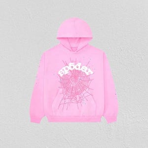 K&ouml;nnte beinhalten: Ein hellrosa Kapuzenpullover mit Kapuze und Vordertasche. Auf der Vorderseite des Hoodies befindet sich ein Spinnennetz-Design mit dem Wort "sp5der" in wei&szlig;er, stilisierter Schrift. Die &Auml;rmel haben kleine, verstreute Details.