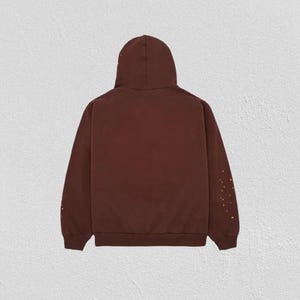 K&ouml;nnte beinhalten: Ein weinroter Kapuzenpullover mit Kapuze und langen &Auml;rmeln. Die &Auml;rmel haben ein Muster aus kleinen goldenen Punkten. Der Hoodie ist aus weichem Material und f&uuml;r den Freizeitgebrauch geeignet.
