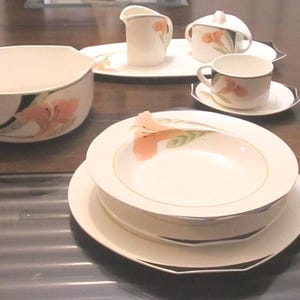 May include: A set of white porcelain dishes with a floral design. The set includes a bowl, a creamer, a sugar bowl, two teacups, and two saucers.