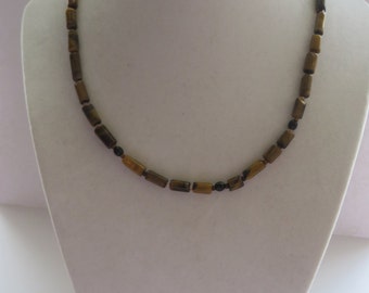 May include: A necklace with rectangular, brown beads and small black beads. The necklace is displayed on a white mannequin. The beads have a tiger eye appearance. The necklace is a jewelry item.