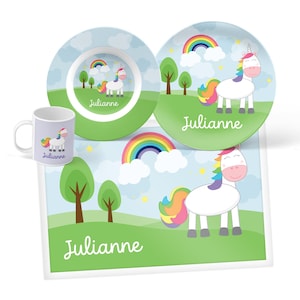 May include: A dining set consisting of a mug, a bowl, a plate, and a rectangular placemat. Each item features a white unicorn with a rainbow mane and tail, a rainbow, clouds, and green trees. The name Julianne is printed on every piece.