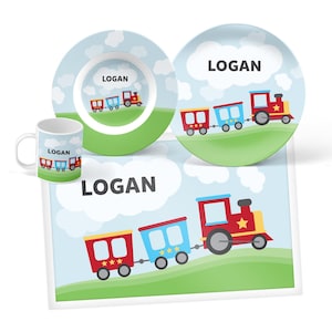 May include: A dining set consisting of a mug, a bowl, a plate, and a rectangular placemat. Each item features a light blue sky with white clouds, a green grassy hill, and a red and blue train graphic with the name LOGAN printed in black text.