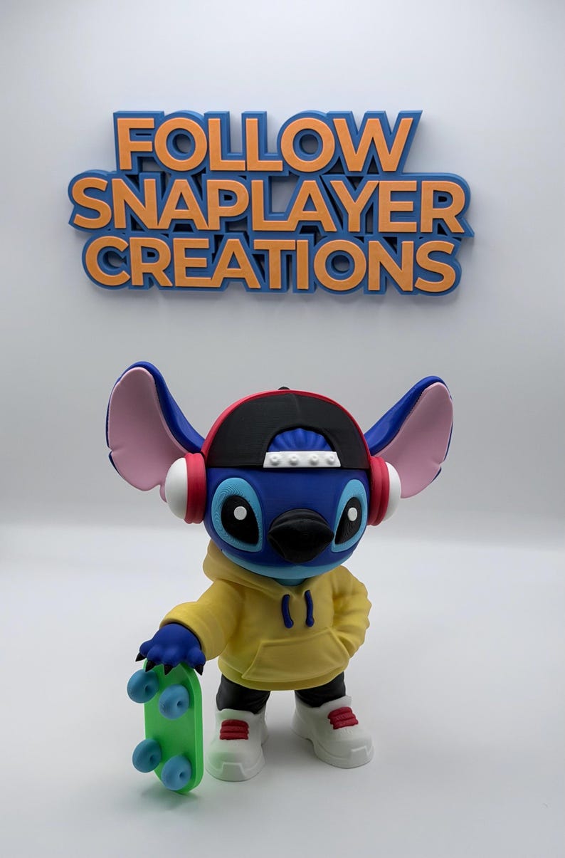 May include: A blue Stitch figurine wearing a yellow hoodie, black and red cap, and headphones, holding a green skateboard. The figurine has white sneakers with red accents. The text "FOLLOW SNAPLAYER CREATIONS" is above.
