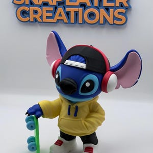 May include: A blue character figure wearing a black cap, yellow hoodie, and white sneakers, holding a green skateboard. The figure has pink ears and red headphones. The text "FOLLOW SNAPLAYER CREATIONS" is above the figure.