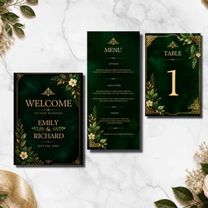 Puede incluir: Un conjunto de papelería de boda que incluye un cartel de bienvenida, un menú y una tarjeta de número de mesa. Cada pieza tiene un fondo verde esmeralda oscuro con bordes dorados, texto en oro y flores blancas con hojas.
