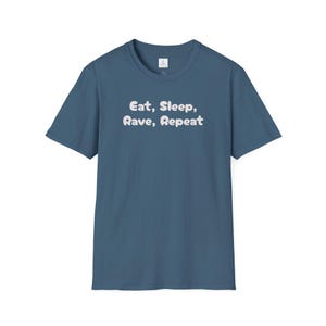 Könnte beinhalten: Blaues T-Shirt mit dem Text "Eat, Sleep, Rave, Repeat" in weißer, abgerundeter Schrift. Das Shirt hat eine einfarbige Farbe und scheint aus einem weichen Material zu sein. Das Design ist mittig auf der Vorderseite des Shirts platziert.