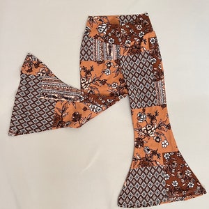 Op de afbeelding: Bruine en witte gebloemde broek met een wijde pijp en een bloemen- en geometrisch patroon.
