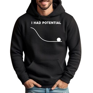 May include: A black hooded sweatshirt featuring a white graphic print on the chest. The graphic displays the text I HAD POTENTIAL above a line drawing of a curved slope with a small circle resting at the bottom, representing a physics concept.
