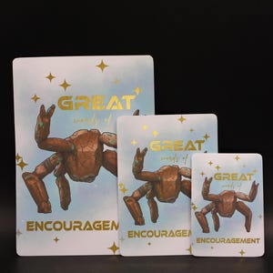 May include: Three rectangular cards of varying sizes featuring a brown rock-like crab illustration on a light blue background with gold stars. The text reads "GREAT words of ENCOURAGEMENT" in gold lettering across the center and bottom of each card.