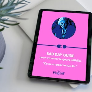 May include: A tablet displays a pink screen with the text "BAD DAY GUIDE" and French text below. A blue graphic of a person is in a circle at the top. The tablet is on a white surface next to a potted plant.